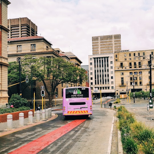 red and white bus on road near brown concrete building during daytime in Pretoria South Africa