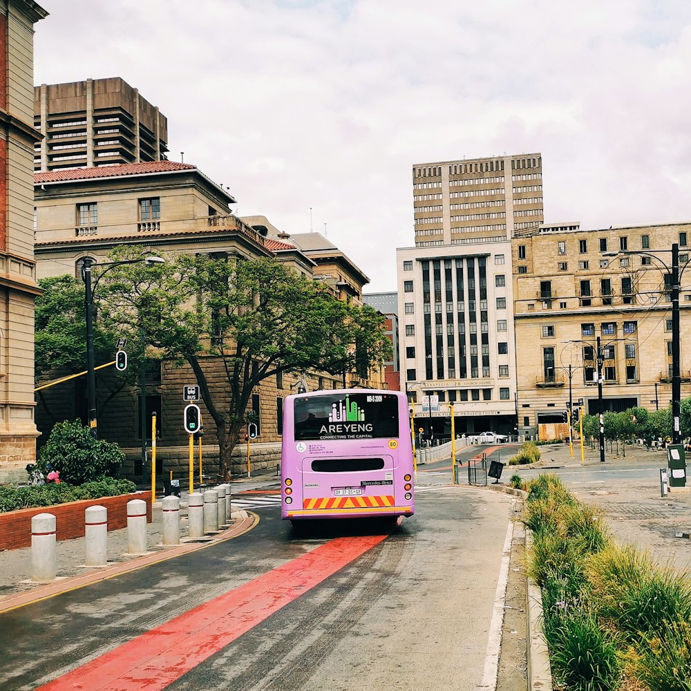 red and white bus on road near brown concrete building during daytime