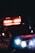 An ambulance with emergency lights flashing is visible in a dark setting. The vehicle is branded with 'Denver Health' on the side and the lights create a strong contrast against the darkness.