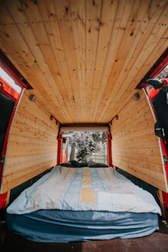 Artistic shot of a van bed platform made of natural wood, highlighted by soft light.