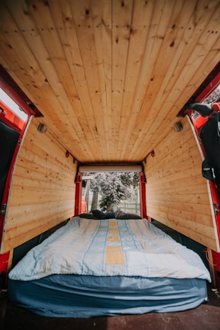 A cozy van interior showing a custom window with a view of a forest.
