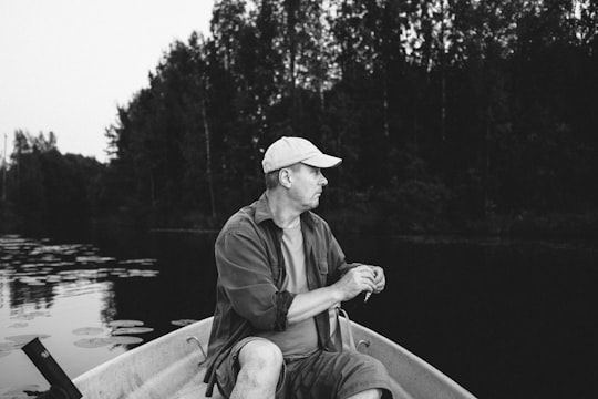 man in black jacket and brown hat sitting on boat in Orivesi Finland