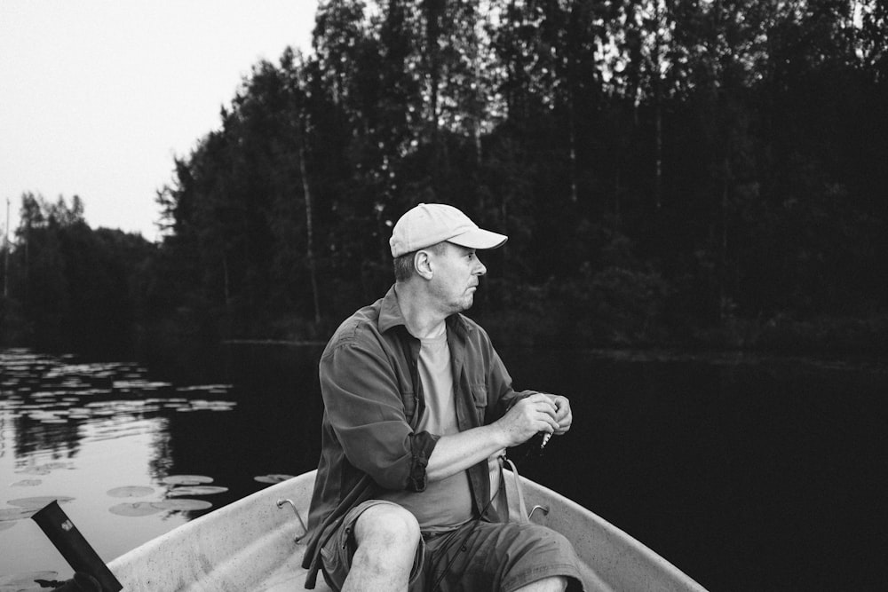 homme en veste noire et chapeau marron assis sur le bateau