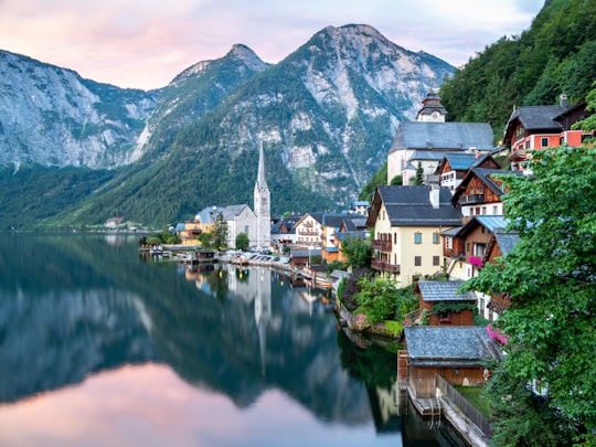 brown and white concrete houses near lake and mountain under blue sky during daytime in Hallstatt Austria Austria