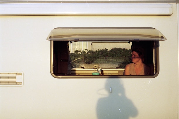 Annette working on her laptop inside her cozy motorhome with a scenic European landscape outside.