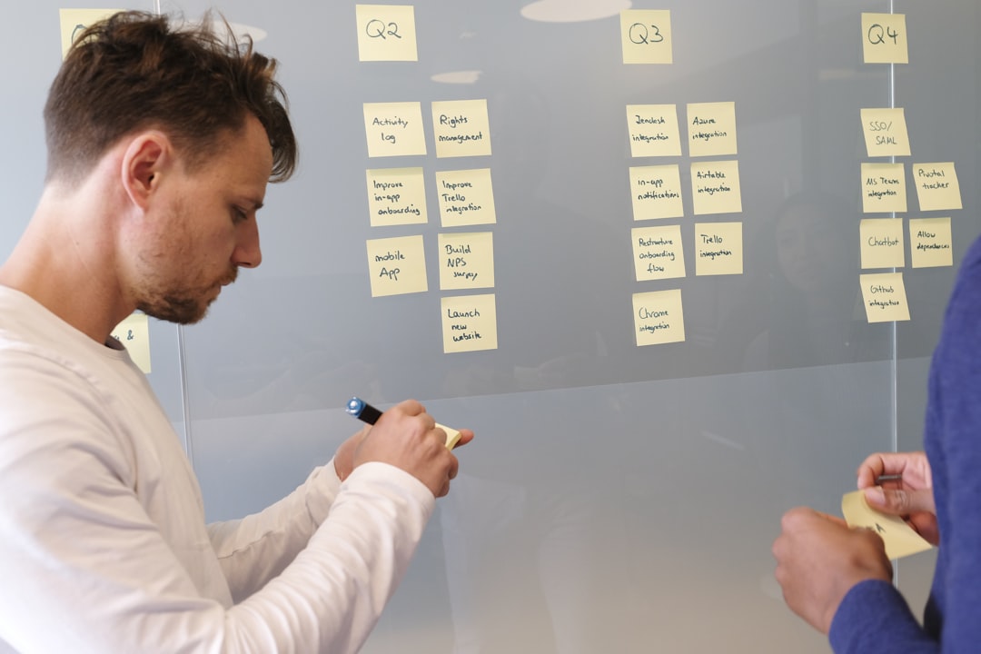 man in white long sleeve shirt writing on white board, CEO planning and prioritizing the quarter with the team.
