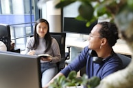 A smiling instructor giving feedback to a student working on a creative writing assignment.