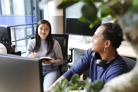 A friendly consultant sitting at a desk, discussing writing strategies with a smiling client.