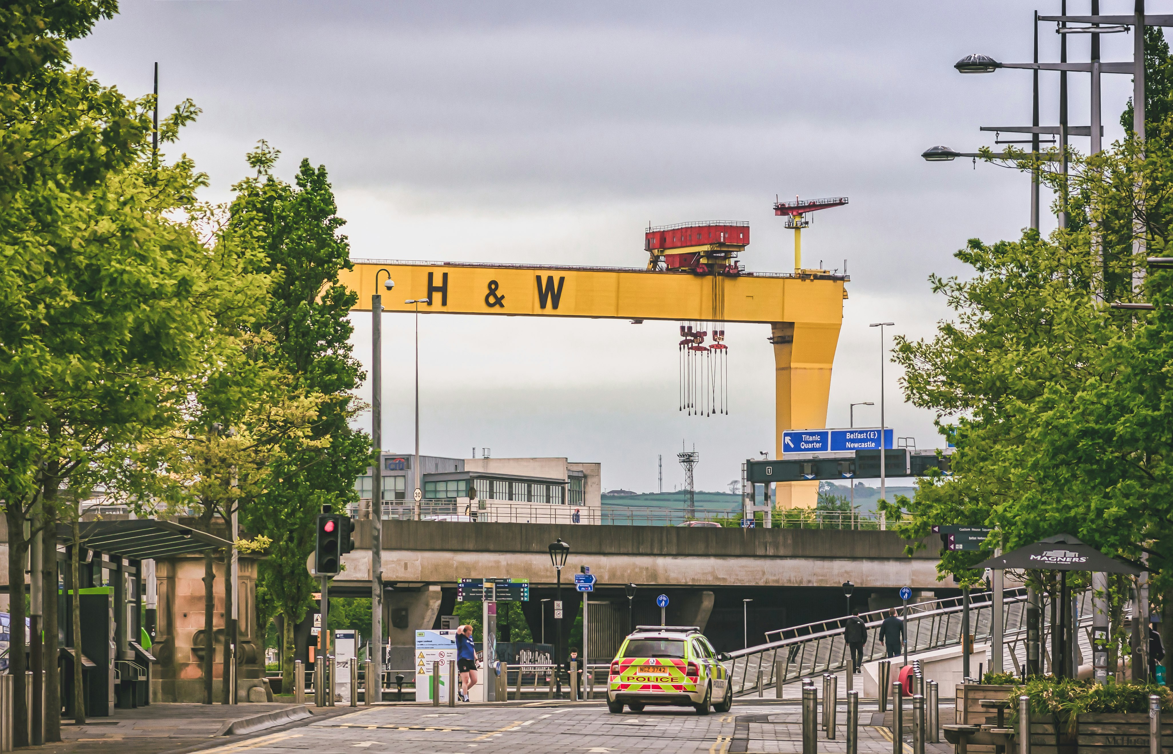 Police patrol the near-empty streets of Belfast during during lockdown due to the Covid-19 Pandemic whilst Samson, the ship-building crane, stands watch in the background (May, 2020).