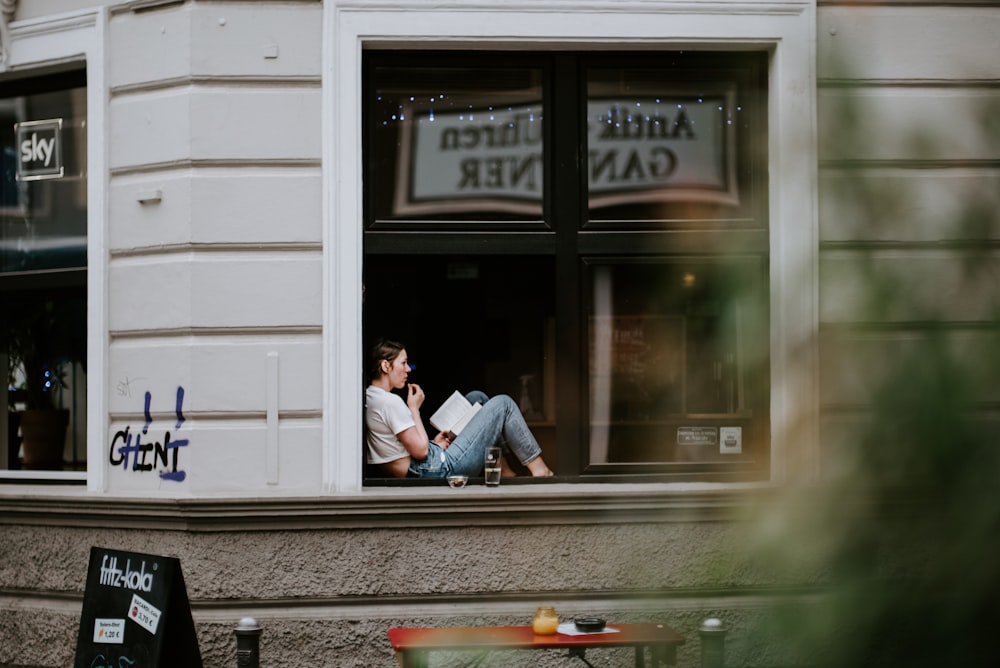 man in blue dress shirt and blue denim jeans sitting on bench