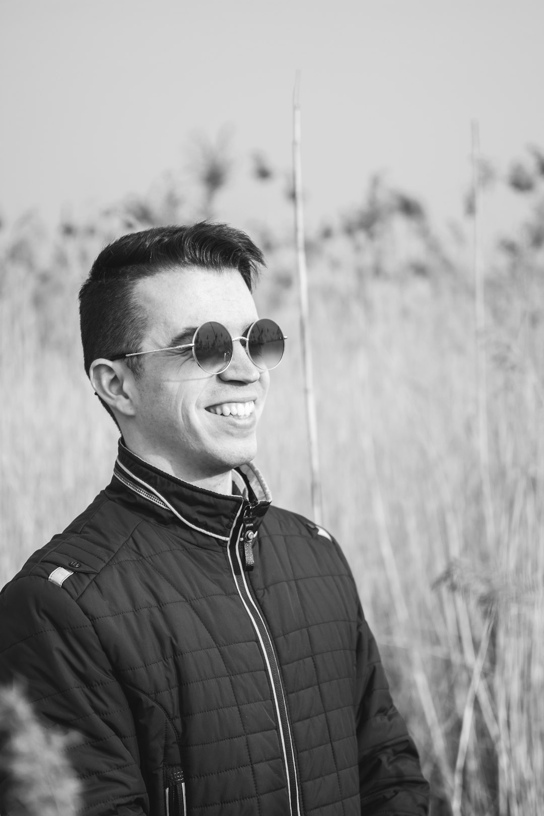 grayscale photo of man wearing sunglasses and plaid shirt