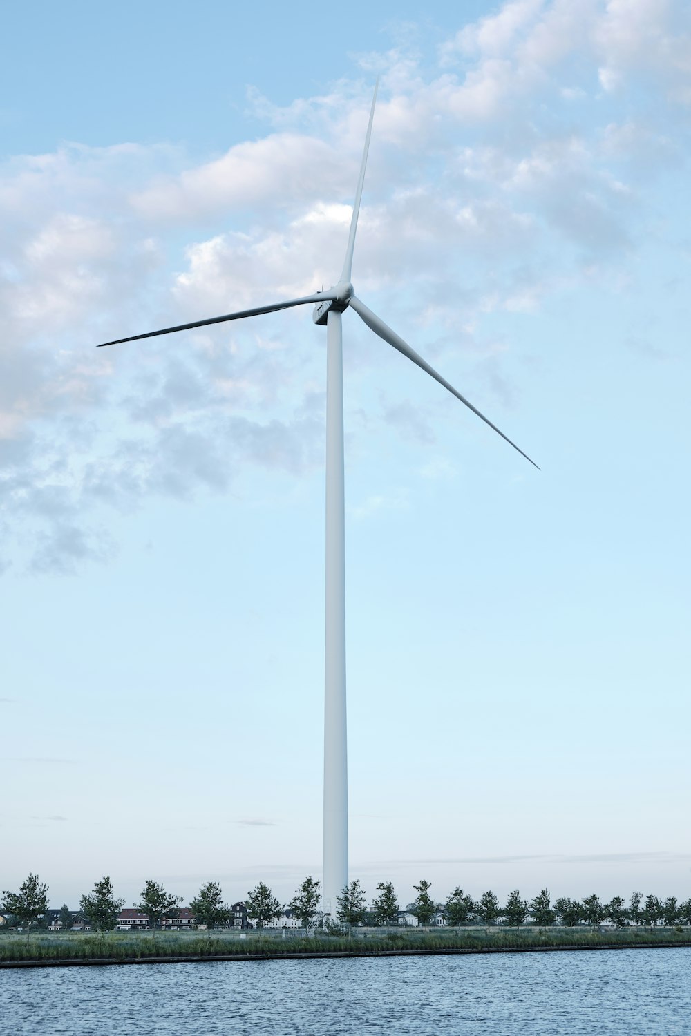 white wind turbine under white clouds during daytime