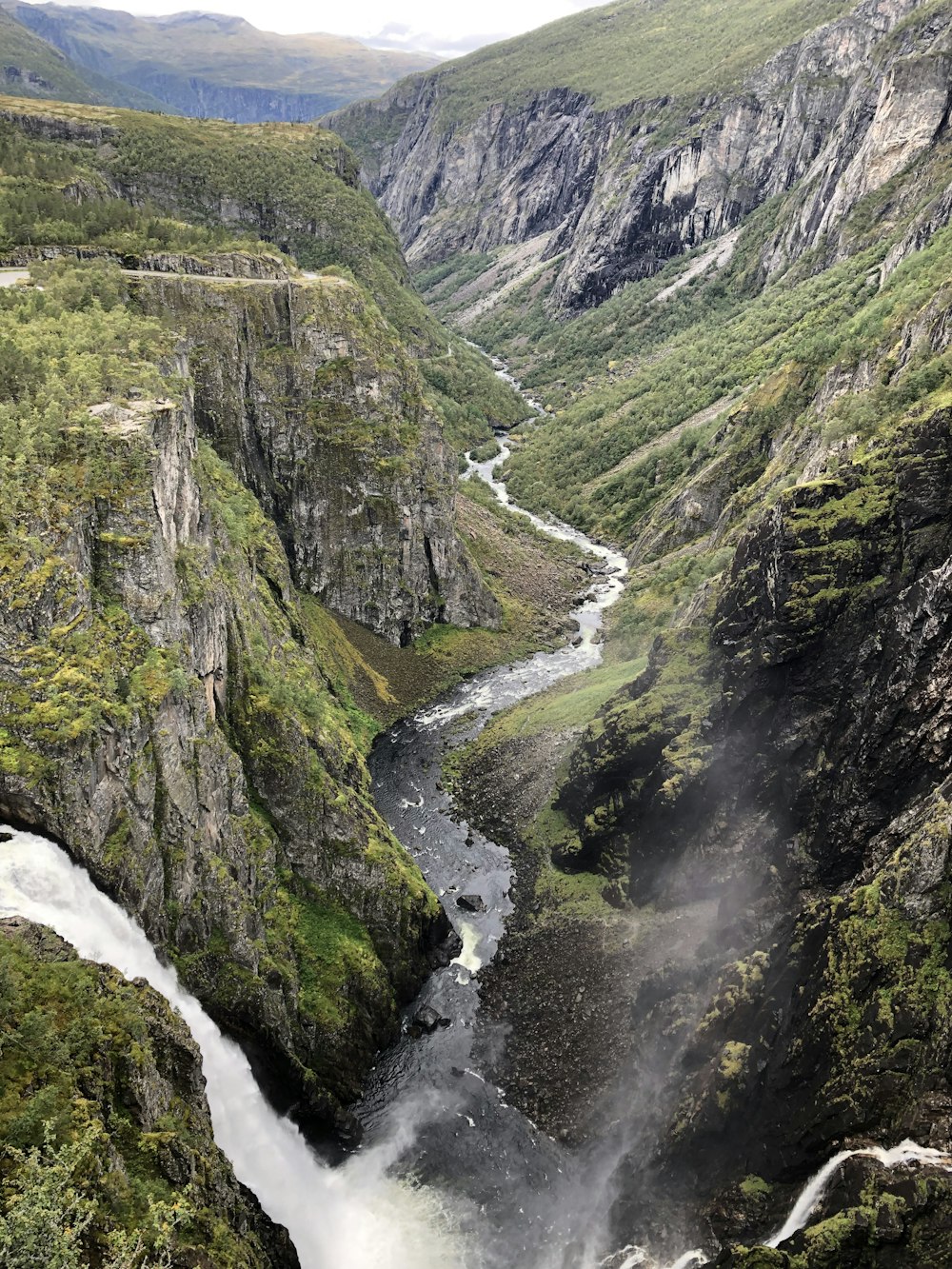 river between green and brown mountains during daytime