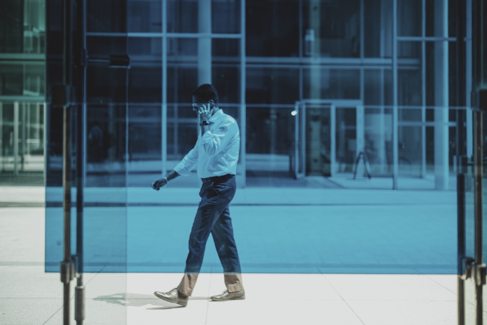 man in blue dress shirt and black pants standing on blue floor