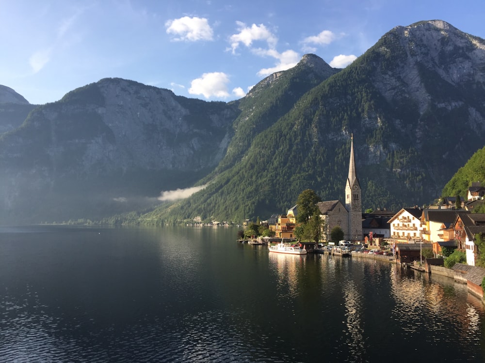 Casa marrone e bianca vicino allo specchio d'acqua e alla montagna verde durante il giorno