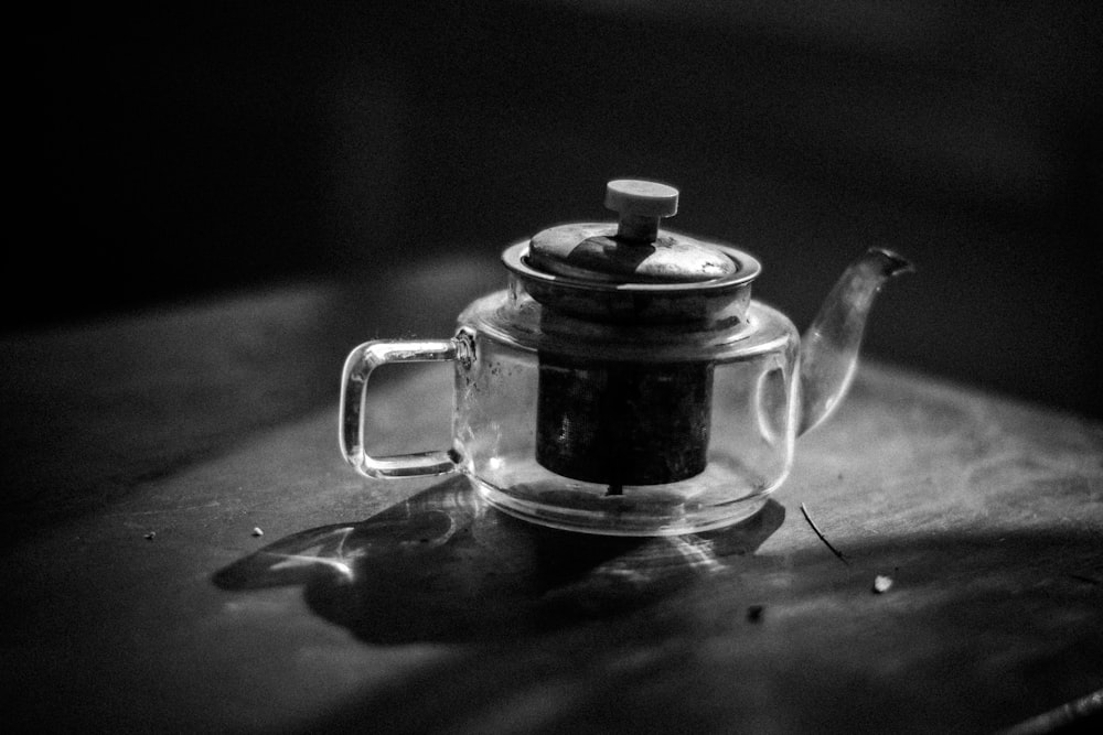 foto em tons de cinza do bule de chá na mesa