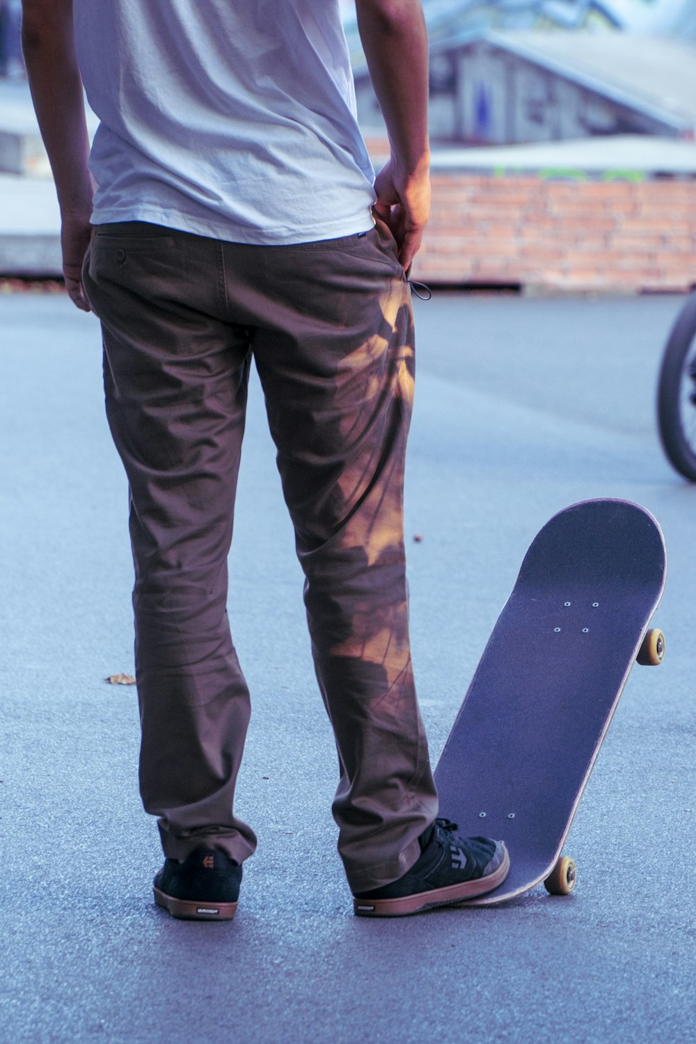 man in gray shirt and brown pants holding black skateboard