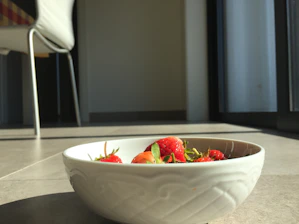 A cozy setup featuring a handmade clay bowl filled with fresh fruit, sunlight streaming through linen curtains.