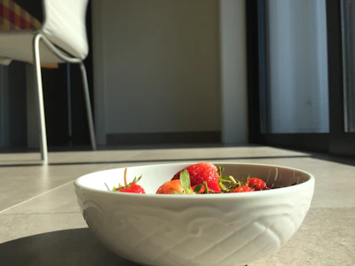 A cozy setup featuring a handmade clay bowl filled with fresh fruit, sunlight streaming through linen curtains.