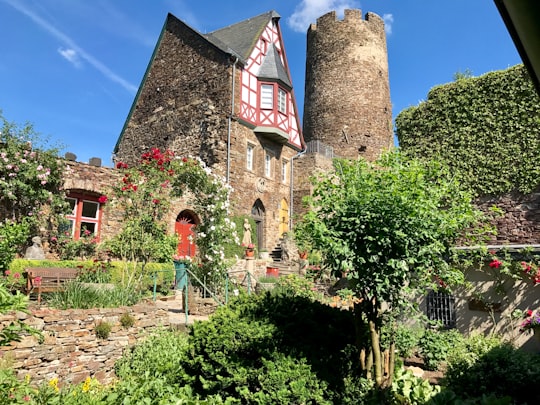 woman in red jacket standing near brown brick building during daytime in Rhineland-Palatinate Germany