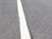 A close-up view of a textured asphalt road with a single white line running through the center.