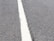 A close-up view of a textured asphalt road with a single white line running through the center.