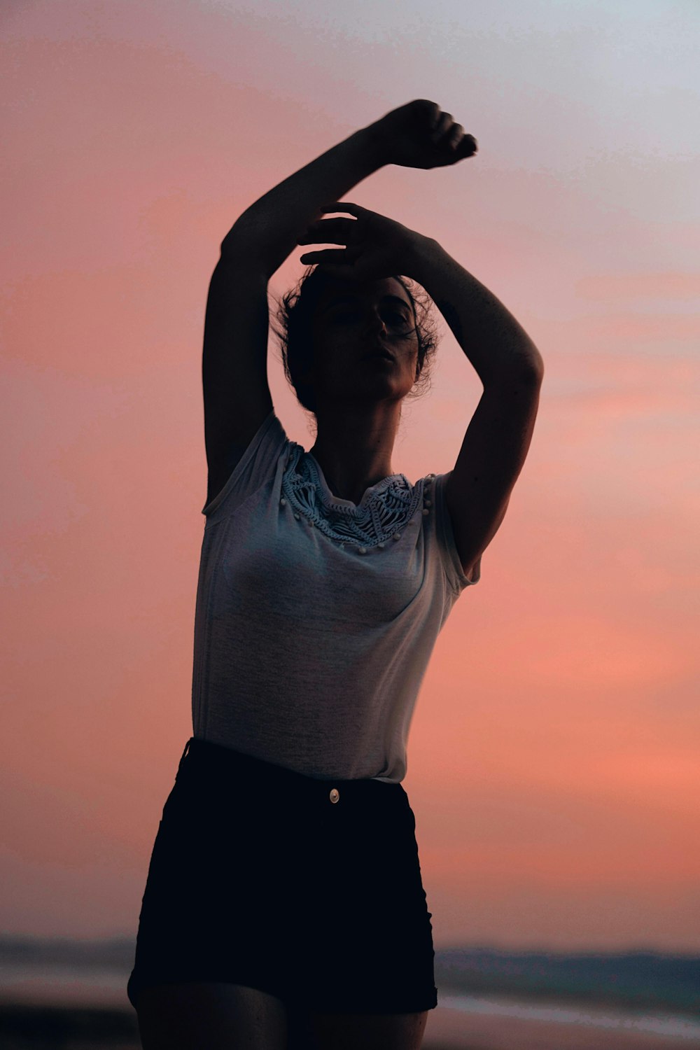 woman in white tank top and black pants raising her hands