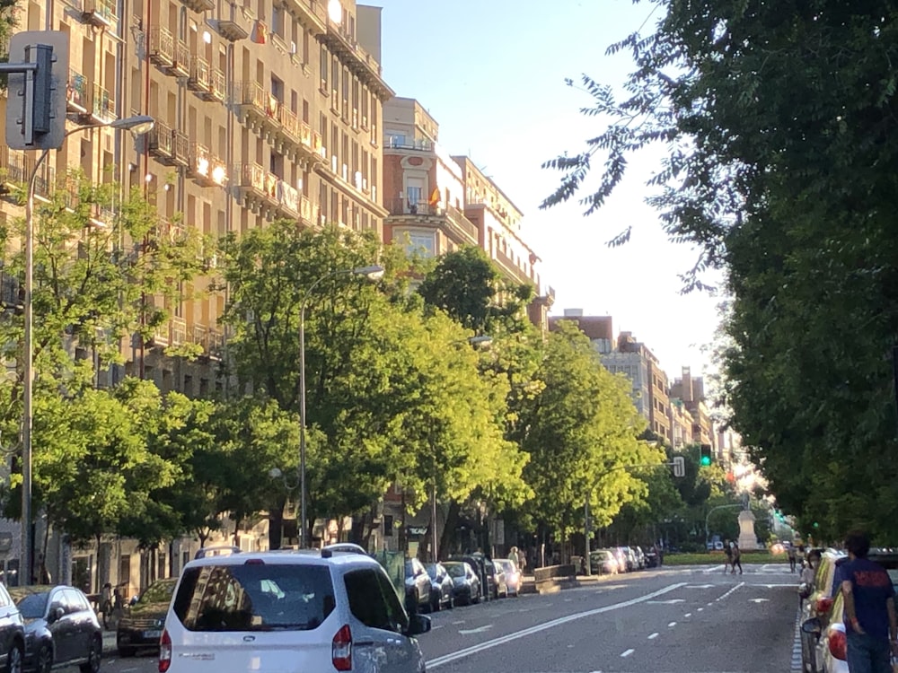 cars parked on side of the road near high rise buildings during daytime