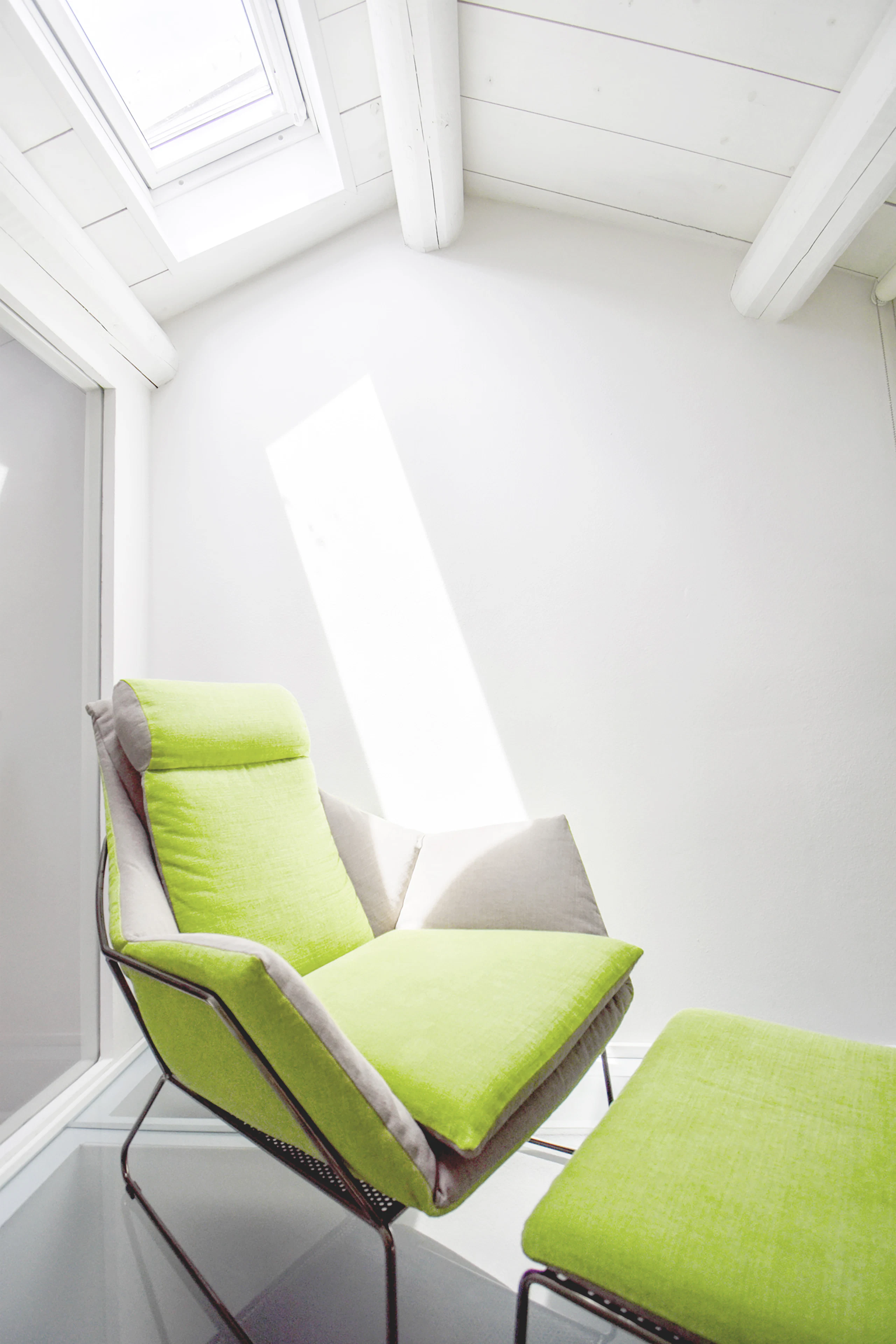 A chair beneath a shaft of light from a skylight