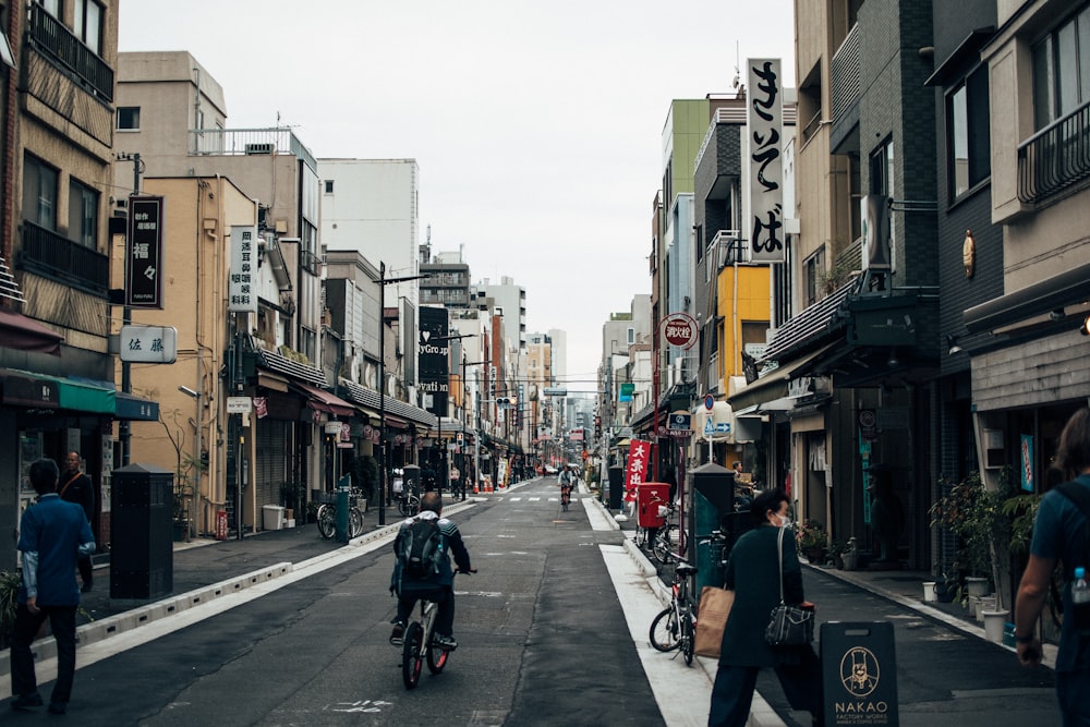 people riding bicycles on road between buildings during daytime