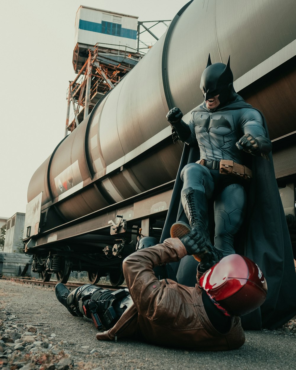 man in black jacket and brown pants wearing red helmet sitting on black metal tank during