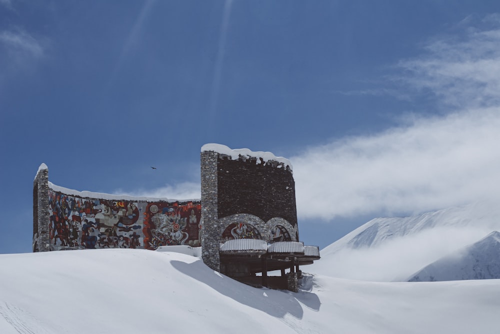 昼間の青空の下、雪に覆われた地面に茶色の木製のベンチ