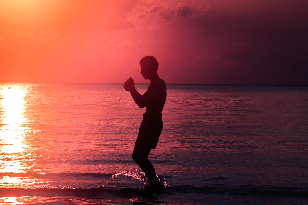 silhouette of man standing on beach during sunset