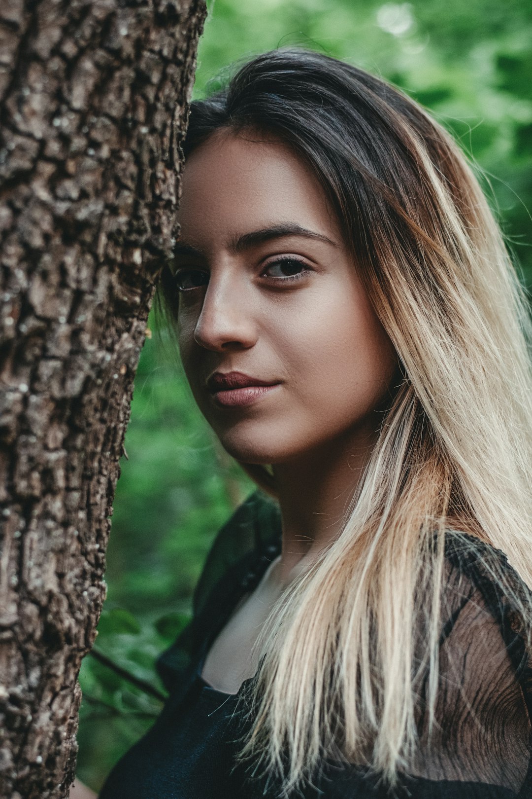 woman in green shirt beside brown tree