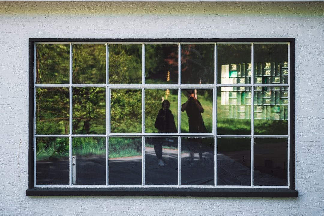 man in black suit standing in front of white framed glass window