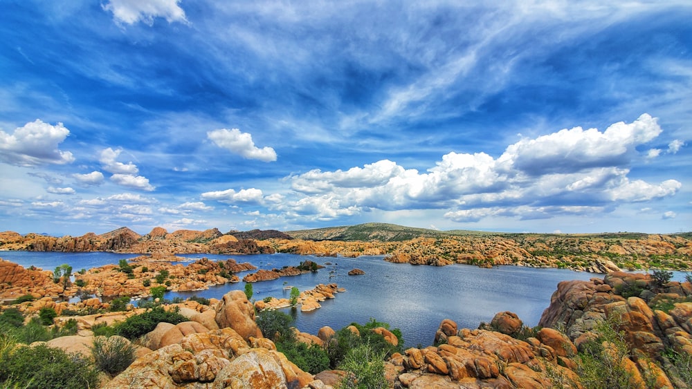 brown rocks on body of water under blue sky and white clouds during daytime