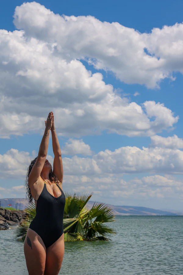 Woman stretching her arms overhead against a cloudy sky