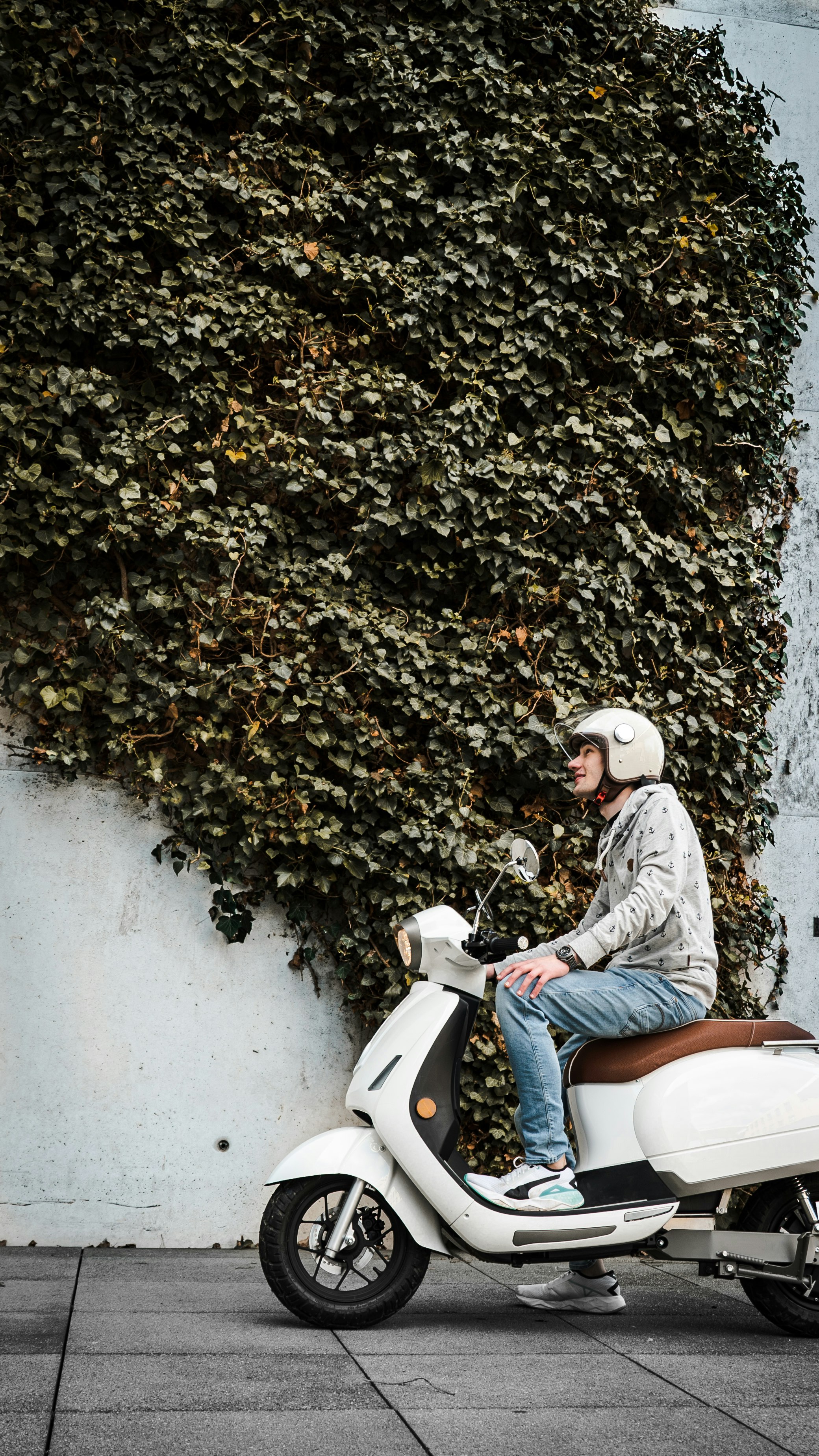 A 16:9 picture of a young man sitting on the electric Kumpan 54 Ri scooter. 