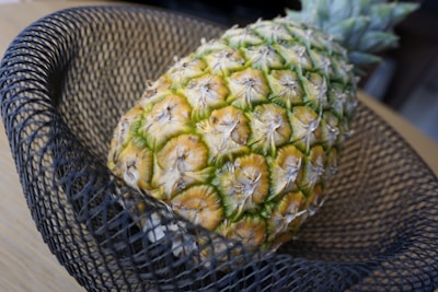 Close-up of a vibrant pineapple fruit bowl glowing softly on a black marble table.
