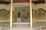 A peaceful chapel interior with wooden pews and a statue of the Virgin Mary adorned with flowers.