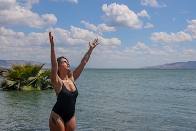 woman in black tank top standing on beach under blue sky during daytime