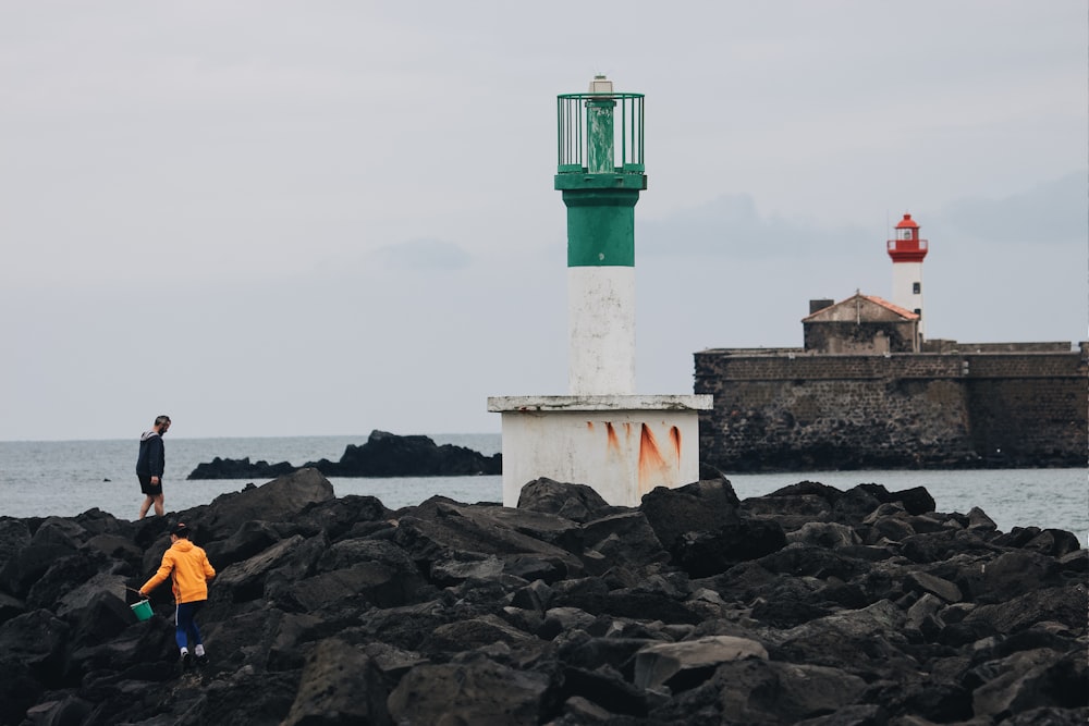 white and green lighthouse on brown rocky shore during daytime