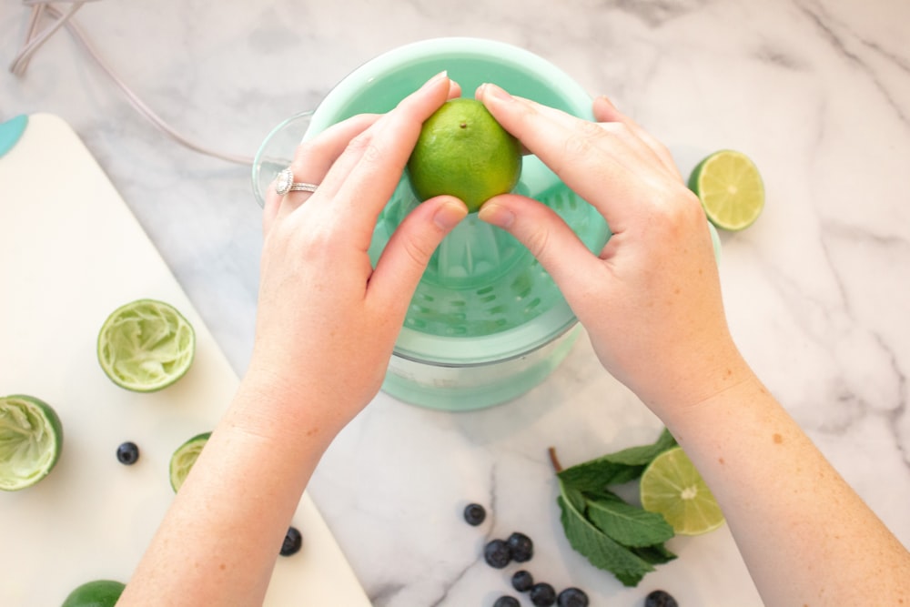 person holding clear glass cup with sliced lemon