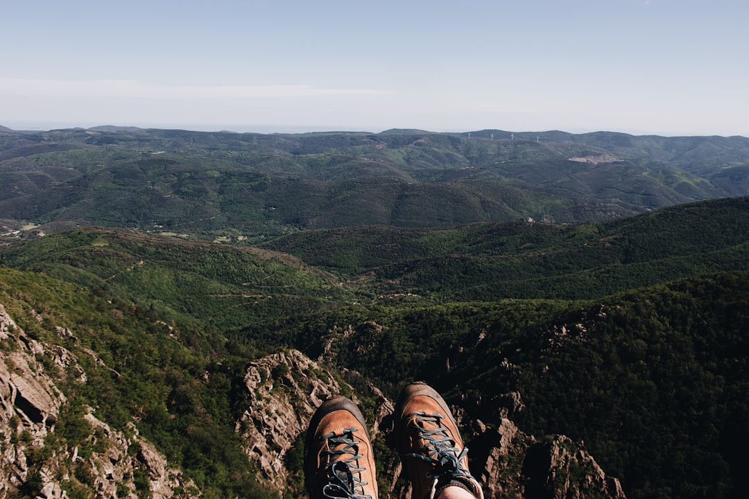 person in black hiking shoes on mountain during daytime