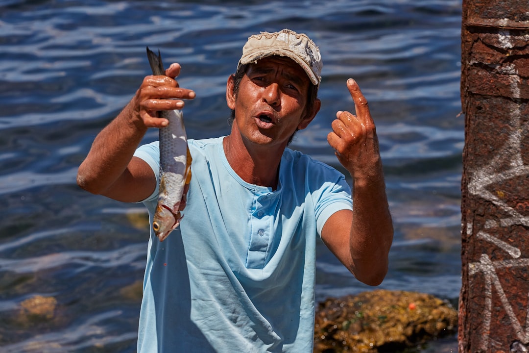 man in white crew neck t-shirt holding brown fish