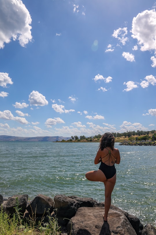 woman in black bikini standing on sea shore during daytime in Sea of Galilee Israel