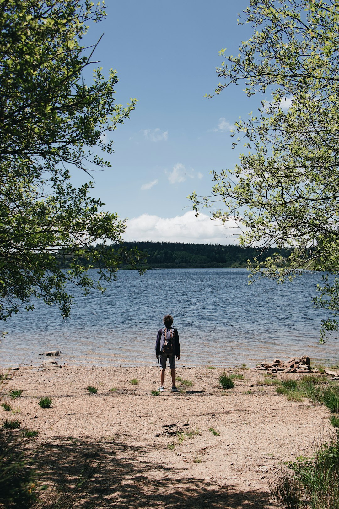 man in black jacket standing on brown sand near body of water during daytime