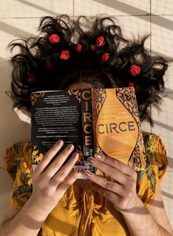 woman in yellow and brown floral dress holding black and brown book