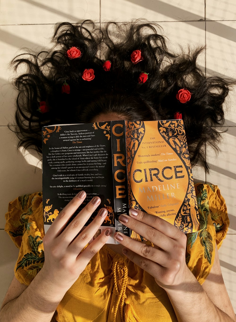 woman in yellow and brown floral dress holding black and brown book