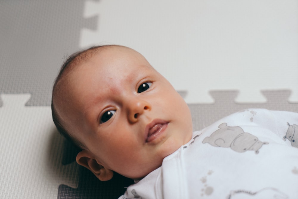 a close up of a baby laying on a mat